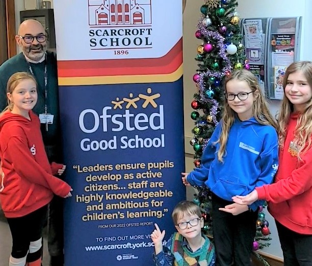 Image of headteacher and students at Scarcroft Primary School celebrating their Good Ofsted result